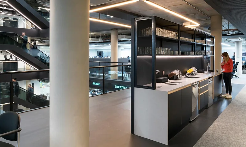 An open office floor with a feature stair, exposed services and glazed partitions
