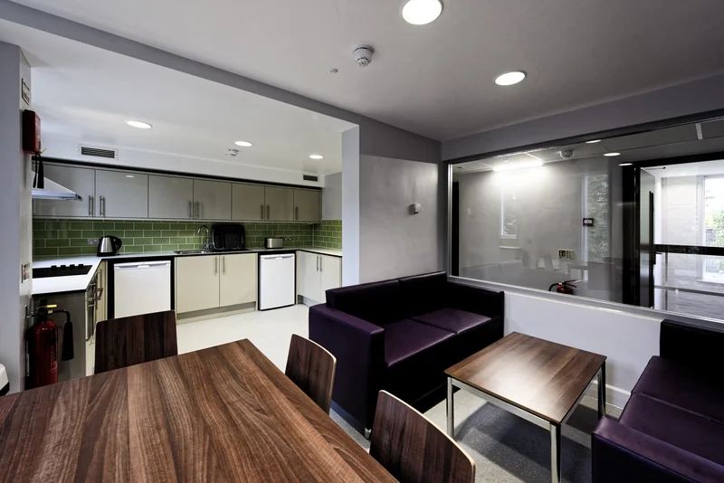 A communal kitchen and dining area with timber doors and a glazed screen
