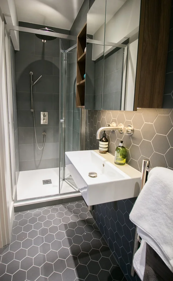 An apartment bathroom with a walk in shower, basin and hexagonal floor tiling