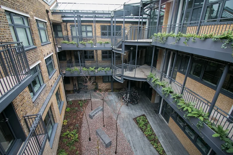 A residential courtyard seen from above, with brick elevations, walkways and planting