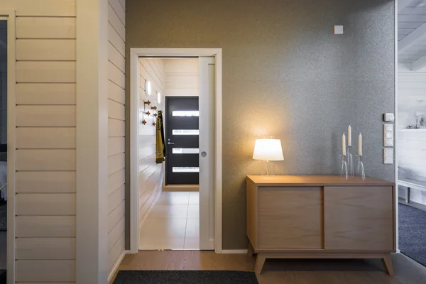 A residential hallway with a sideboard and a panelled door with a dark lever handle