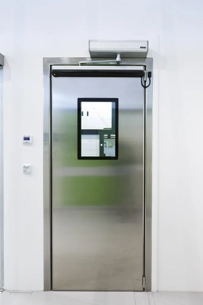 A single automatic swing door in a stainless steel frame with a vision panel and a wall mounted activation plate