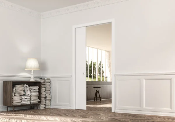 A single pocket door slid open into the wall between a hallway and a dining room, with no architrave visible on the opening
